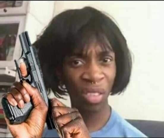 Meme ⚡ Anh da đen tóc ngắn giả gái cầm súng lên đạn chuẩn bị bắn